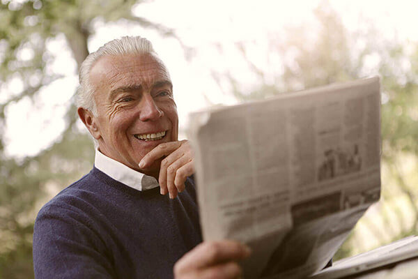 an elderly man reads the paper